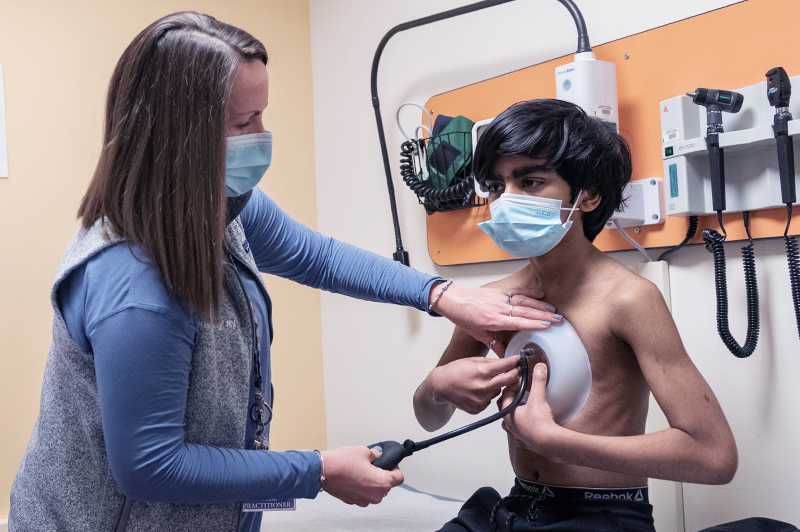 A nurse practitioner shows a young man how vacuum bell therapy for pectus excavatum works.