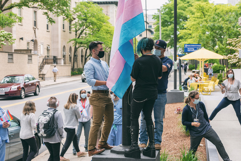 Evan raises the transgender and rainbow flags, along with fellow GeMS patient Brandon Adams (left).