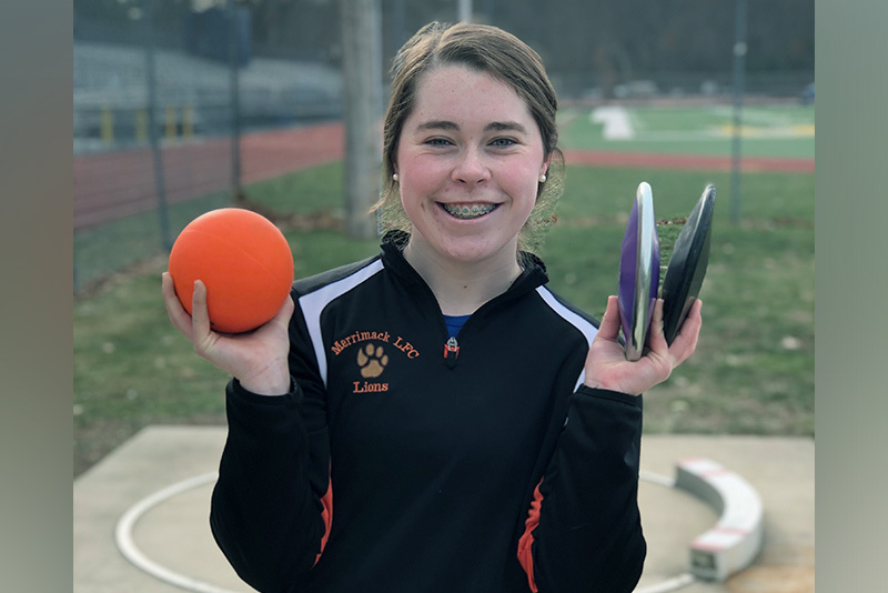Abby holds two discuses and a shotput