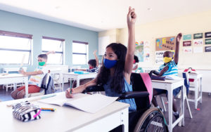children raising hands in a classroom