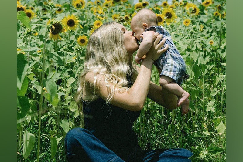jada holds her baby in a field of sunflowers