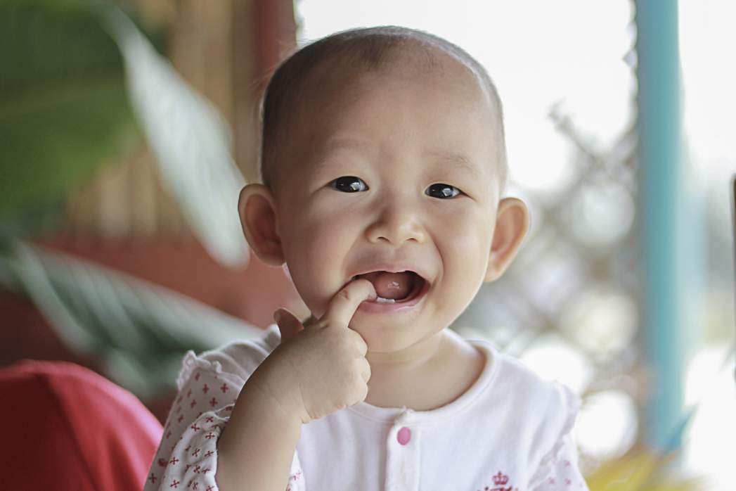 a teething baby with a finger in her mouth