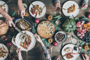 People at a dining table fill their plates with food.