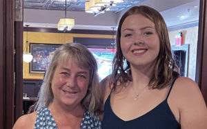 Woman and teenage girl standing next to each other smiling