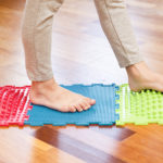 a child with flexible flatfoot walks on a colorful mat.