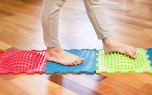 a child with flexible flatfoot walks on a colorful mat.