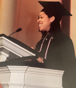 Tyonne Hinson, at a podium, wearing a cap and gown. 