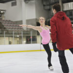 A figure skater practices with her coach.