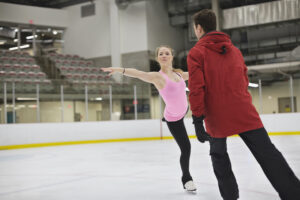 A female figure skater practices with her coach.