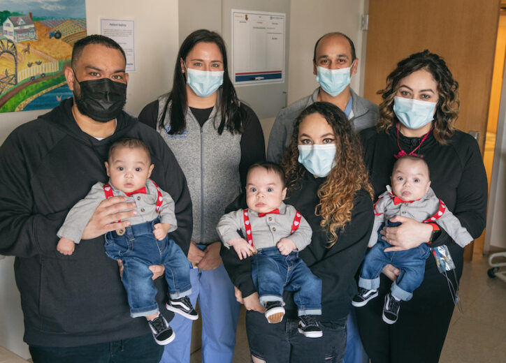 Makai's parents and older sister hold him and his two brothers. Dr. Biren Modi and Megan Gray, on his short bowel care team, stand with them.