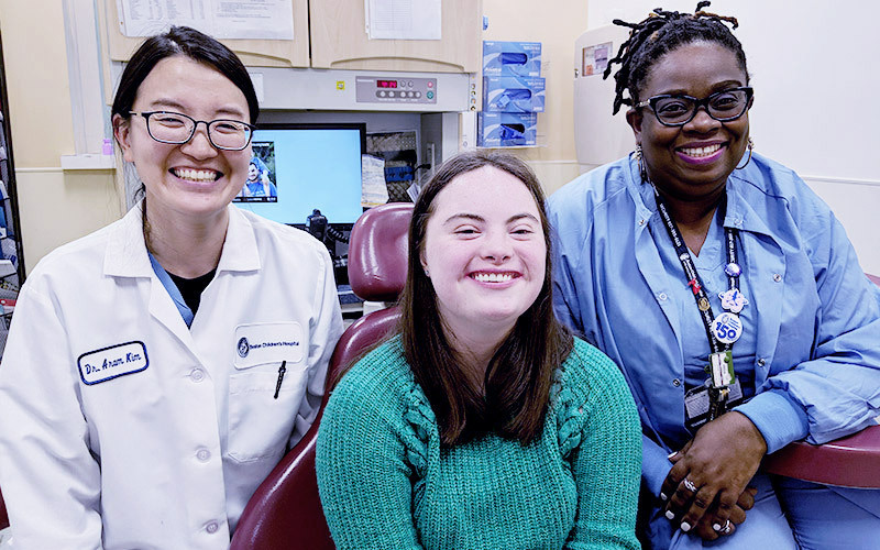 Amanda Altemus  is surrounded by prosthodontist Aram Kim, DMD, on her left and Marie Courtois, the Prosthodontics Program clinic supervisor, on her right.