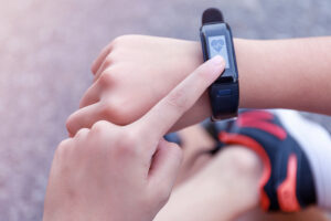 The photo is a closeup of a child's left index finger touching the screen of a wearable device on the right wrist.