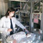Alt text: Newborn Medicine physician Sarah Morton, MD, PhD, attending a baby girl in the NICU.