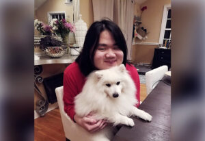 Adolescent boy holding a white dog at a dinner table