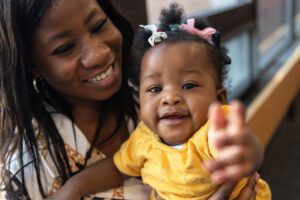 Theresah smiles while her daughter Eno reaches toward the camera. Both mother and daughter were born with clubfoot