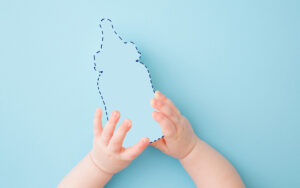 a baby's hands hold the outline of a baby bottle