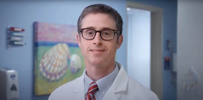 Dr.Caleb Nelson wearing glasses and smiling