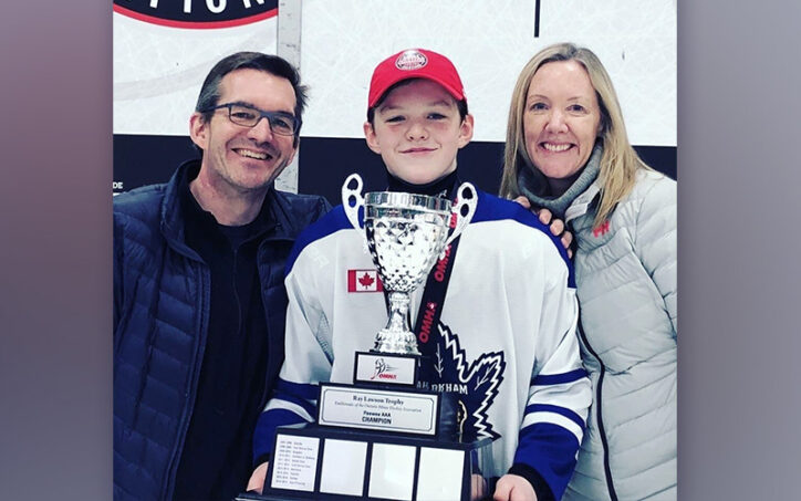 Grady, who had osteochondritis dissecans, posing with an enormous hockey trophy and his parents.