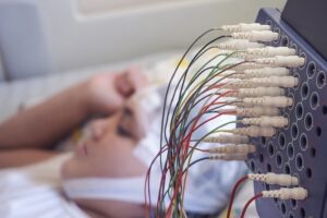 A girl lying in bed undergoing electroencephalography.