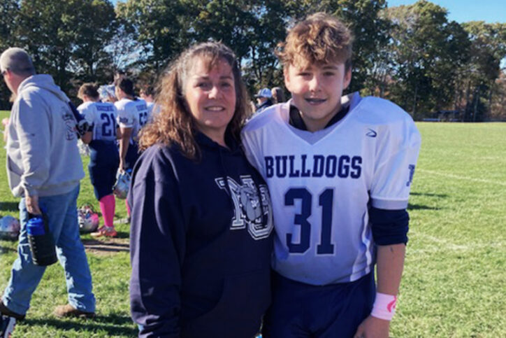 Quinn, who had flexible flatfoot, in a football uniform stands with his mother after a game.