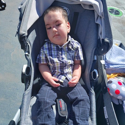 Noyan, a toddler with hypotonia, in his stroller