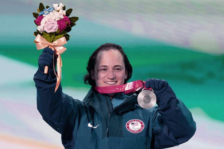 Thomas holds up a bouquet of flowers and his silver medal at the Bejing Paralympics.