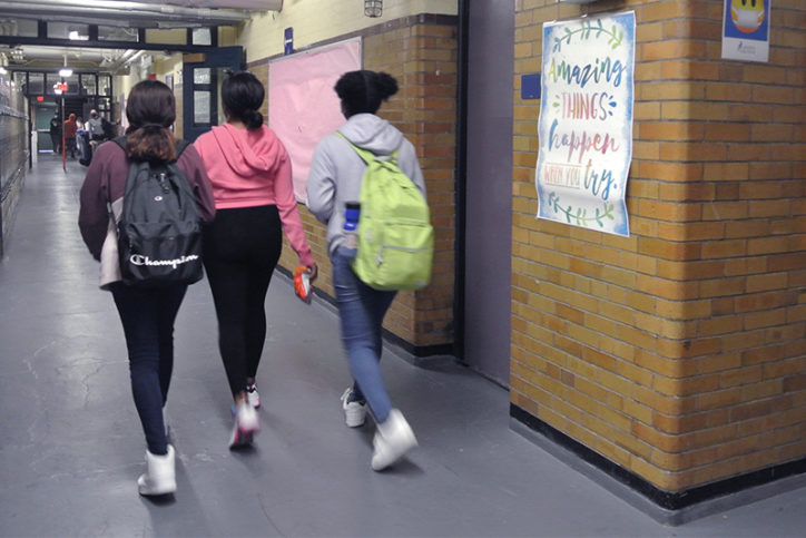 Three teen girls walk down the hallway of a school where BCHNP offers behavioral health services.