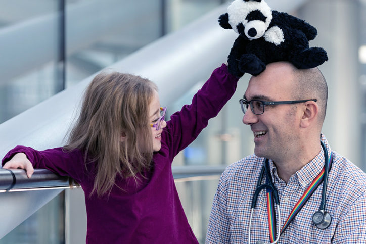 Addison playfully puts her stuffed panda bear on Dr. Tom's head.