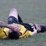 Injured soccer player lays on the field. Clavicle fracture is a common sports injury.