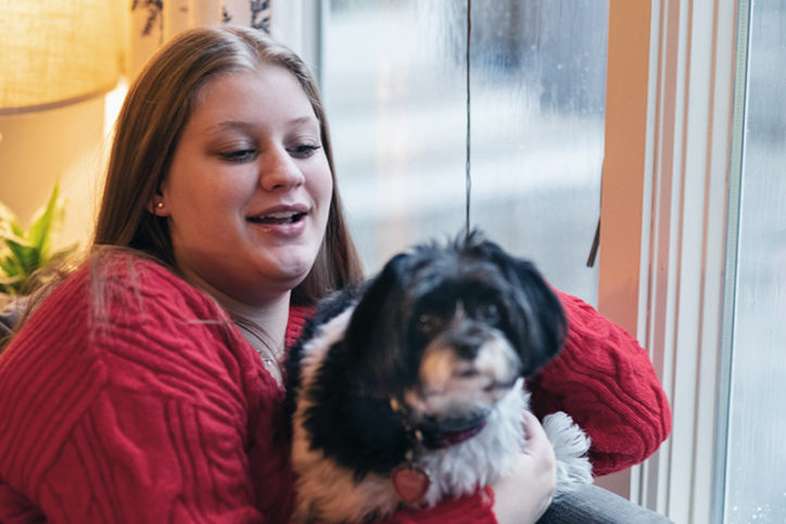 Paige, six months after a post-surgical nerve block boosted her recovery, pets her dog.