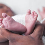 a hand holding an infant's feet