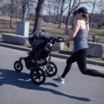 Female athlete sprints while pushing a baby stroller.