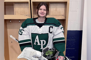 A high school hockey goalie in her uniform and gear.