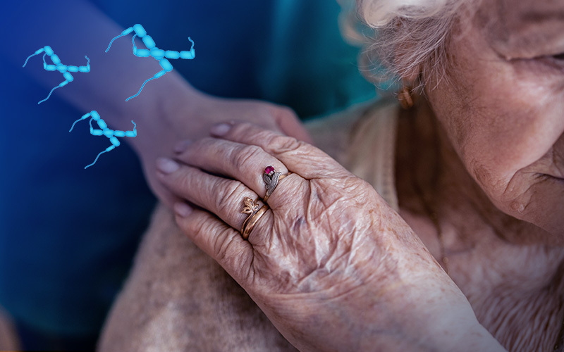 An elderly woman presumably with dementia, holding the hand of a caregiver, with tau molecules added.