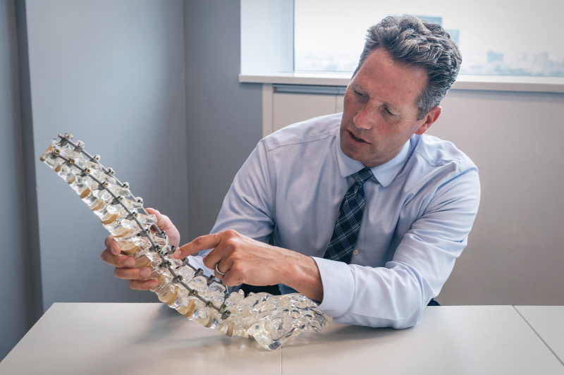 Dr. Hedequist looks at a model of a spine after spinal fusion surgery.