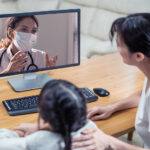A young girl and her parent speak with a clinician on a virtual appointment.