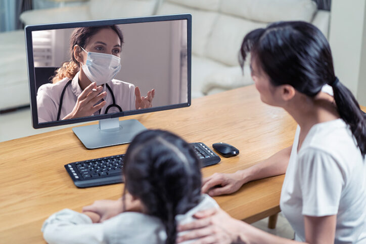 A young girl and her parent speak with a clinician on a virtual appointment.