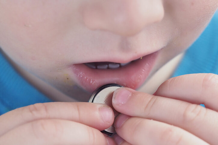 a child holding a button battery up to their mouth