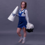 Becca Hudson in her college cheerleading costume with pompom and megaphone.