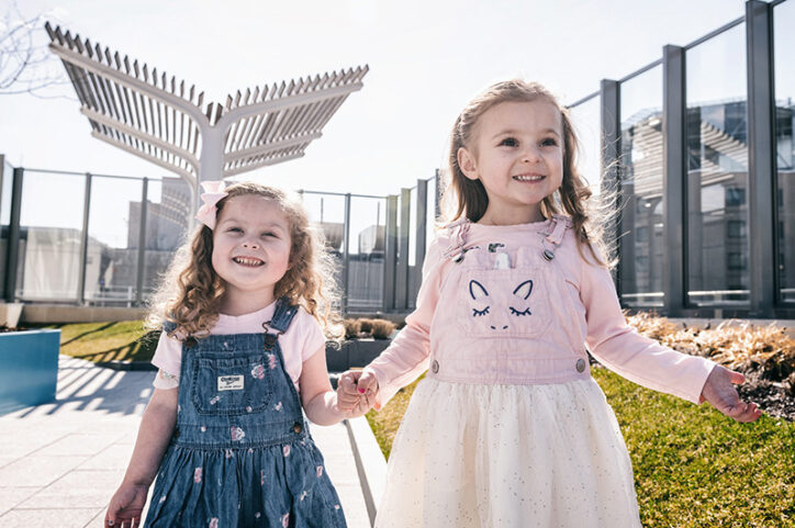 Aubree and Makayla hold hands and smile on the Boston Children's rooftop garden