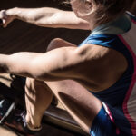 Strong female athlete working out on a rowing machine.
