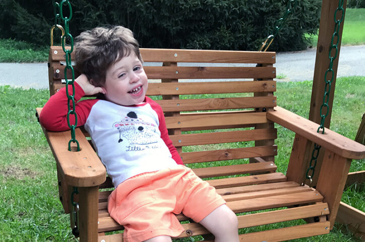 Weston, sitting here on a swing, is thriving thanks to telehealth visits