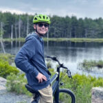 Ethan sits on his bike near a lake in Acadia National Park after treatment for a mixed germ cell brain tumor.
