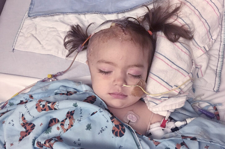 Vanessa in a hospital bed hooked up to oxygen and monitors, with stitches in her scalp.