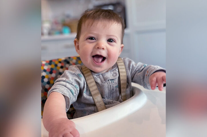 Joey, who had surgery for a megaureter, laughs while sitting in a high chair