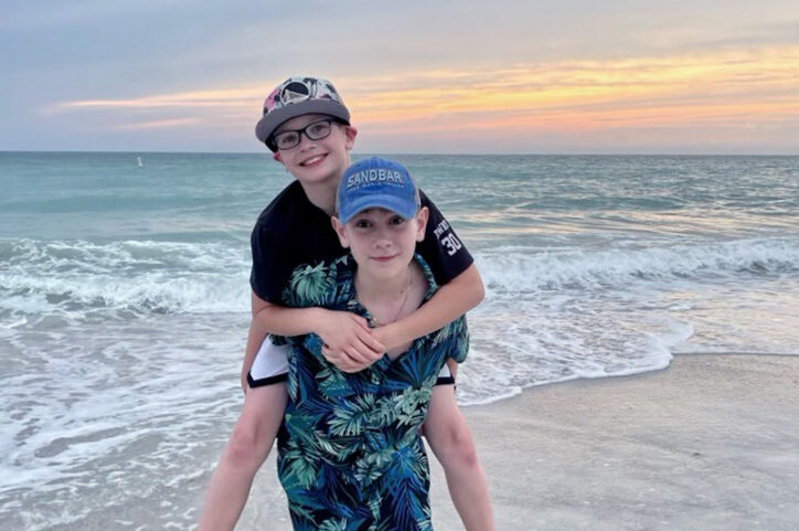 Connor carries his brother on his back at the beach. 