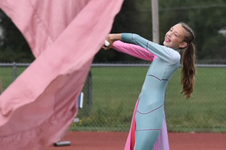 Chloe waves a large pink flag as part of her role on a school color guard squad.