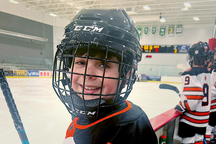 Zachary on a hockey rink, wearing. a helmet
