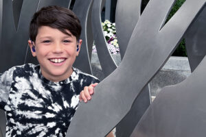 A 9-year old boy smiles proudly with his hearing aids visible.