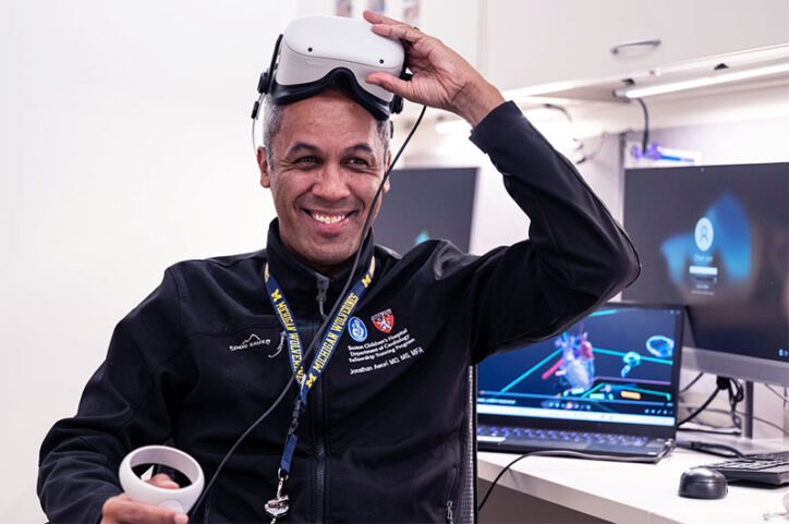 A man pulls virtual reality goggles over his head while smiling.